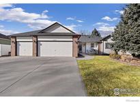 Charming single-story home featuring a three-car garage, well-manicured lawn, and a welcoming brick facade at 2559 Serena Dr, Mead, CO 80542