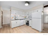 Well-lit kitchen featuring white cabinets, modern appliances, and a light wood-look floor at 4434 Mast Rd, Boulder, CO 80301