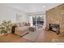 Bright living room features a stone fireplace, tan sectional sofa, and a sliding door to the balcony at 449 Wright St # 6, Lakewood, CO 80228