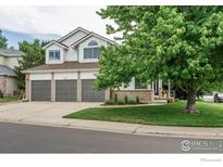 Charming two-story home featuring a three-car garage, brick accents, and a well-maintained front yard with mature tree at 809 Saint Andrews Ln, Louisville, CO 80027