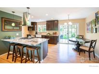 Bright kitchen featuring a granite island, stainless steel appliances, and access to a large, landscaped backyard at 1011 Vivian Cir, Boulder, CO 80303