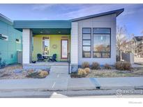 Modern home with a covered porch featuring chairs, stone landscaping, and a bright exterior at 1324 Snowberry Ln, Louisville, CO 80027