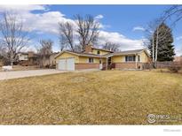 Charming yellow home featuring a well-maintained front yard and a two-car garage at 1614 Meeker Dr, Longmont, CO 80504