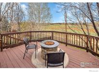 Outdoor deck featuring a stone firepit and chairs overlooking a scenic backyard at 1665 Bain Dr, Erie, CO 80516