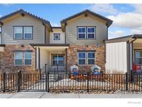 Charming townhome featuring a stone facade, neutral siding, a front porch, and a small metal fence at 2748 Prairie Flax St, Berthoud, CO 80513