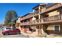 Condominium exterior featuring wood balconies, with a parking area and lush tree at 2877 Shadow Creek Dr # 303, Boulder, CO 80303