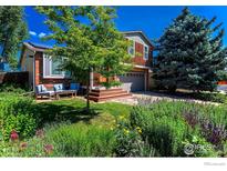 Charming home with a lush landscaped front yard, blue exterior furniture set, and a two-car garage at 359 S Jefferson Ave, Louisville, CO 80027