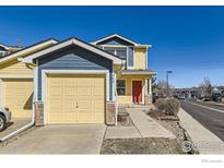 Charming two-story home with a yellow and blue exterior, a two-car garage, and a bright red front door at 400 Smith Cir, Erie, CO 80516