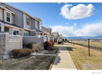 Row of townhomes with neutral siding and stone accents along a sidewalk with mountain views at 4742 Raven Run, Broomfield, CO 80023