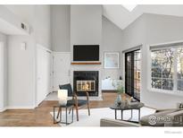 Bright living room featuring a fireplace, hardwood floors, vaulted ceiling, and a large window at 4882 E Kentucky Ave # C, Denver, CO 80246