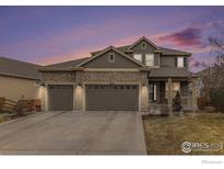 Charming two-story home with stone accents, a three-car garage, and a well-manicured front lawn at 4910 Crimson Star Dr, Broomfield, CO 80023