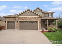 Inviting home featuring a stone facade, three-car garage, and a charming front porch at 4910 Crimson Star Dr, Broomfield, CO 80023