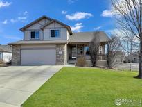 Charming two-story home with a stone-accented facade and a well-manicured lawn and a covered porch at 5288 Buttesfield St, Firestone, CO 80504