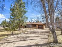 Charming single-story home featuring a brick facade, mature trees, and a long driveway leading to the attached garage at 5692 Pioneer Rd, Boulder, CO 80301