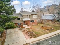 Charming two-story home with a brick facade, mature trees, landscaped front yard, and mountain views at 741 Ithaca Dr, Boulder, CO 80305