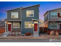 Modern townhome showcasing a gray exterior, complemented by a vibrant red door and contemporary landscaping at 744 Grand Market Ave, Berthoud, CO 80513