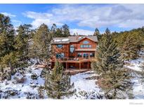 Beautifully designed mountain home with a large deck surrounded by evergreen trees and snow-covered landscape at 84 Canon View Rd, Boulder, CO 80302