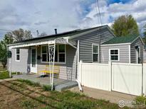 Charming home exterior featuring gray siding, solar panels, covered porch with a yellow bench, and partial white fence at 98 N 12Th Ave, Brighton, CO 80601