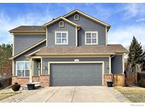 Charming two-story home featuring gray siding, brown brick accents, and an attached two-car garage at 11251 Jersey Way, Thornton, CO 80233