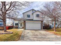 Charming two-story home with a two-car garage, and a well-maintained front yard and walkway at 11537 Macon St, Henderson, CO 80640
