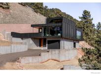 Modern home with black siding, large windows, and terraced landscaping on a hillside at 1575 Linden Dr, Boulder, CO 80304
