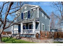 Two story home with blue siding, a white porch, a brick garden, and mature landscaping in the front yard at 1875 Gordon Dr, Erie, CO 80516
