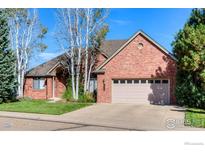 Charming brick home featuring a well-manicured lawn, mature trees, and a two-car attached garage at 2425 Waneka Lake Trl, Lafayette, CO 80026