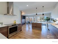 Open kitchen with stainless steel appliances, wood cabinets, kitchen island, and a dining area at 2425 Waneka Lake Trl, Lafayette, CO 80026