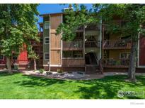 Attractive condo building with wood balconies, green lawn, and mature trees creates a welcoming outdoor space at 2962 Shadow Creek Dr # 105, Boulder, CO 80303