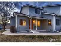 Charming townhome featuring light-blue siding, covered front porch, and a welcoming, brightly painted front door at 500 Lashley St # 58, Longmont, CO 80504