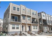 Modern townhome featuring a stone facade, second-story balcony, and neutral siding at 8500 W 62Nd Ave # D, Arvada, CO 80004