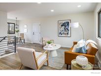 Bright living room with a tan leather sofa, light colored accent chairs, and modern decor at 10792 Moore St, Broomfield, CO 80021