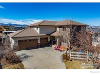 Aerial view of a home with stone accents, a three-car garage, and mountain views in the background at 2005 Calico Ct, Longmont, CO 80503