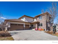 Beautiful home featuring stone accents, a three-car garage, and a welcoming front porch area with chairs at 2005 Calico Ct, Longmont, CO 80503