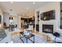 Open-concept living room featuring a fireplace, hardwood floors, and seamless connection to the kitchen and dining area at 5390 Valentia St, Denver, CO 80238