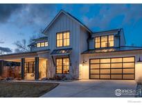 Stunning modern farmhouse exterior with large windows and a glass garage door, illuminated at dusk at 1415 Riverside Ave, Boulder, CO 80304