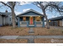 Charming blue single-story home with a cozy front porch and a well-maintained yard with mature trees at 1560 Clinton St, Aurora, CO 80010