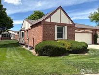 Charming brick home featuring a well-maintained lawn, Tudor accents, and a two-car garage at 2604 Elmhurst Cir, Longmont, CO 80503