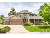 Charming two-story home featuring a brick facade, a three-car garage, and lush landscaping at 366 Blackhawk Ln, Lafayette, CO 80026