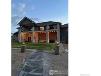 Expansive covered patio with stone pillars and a beautifully landscaped walkway create an inviting outdoor living space at 5489 Country Club Dr, Larkspur, CO 80118