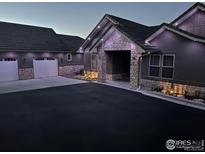 Charming home featuring a spacious driveway, stone accents, and outdoor lighting at 5489 Country Club Dr, Larkspur, CO 80118