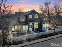 Charming blue townhome with a white picket fence and inviting front patio under a colorful dusk sky at 588 Beauprez Ave, Lafayette, CO 80026