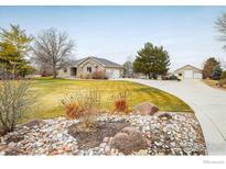 Charming single-story brick home with a well-manicured lawn and an inviting driveway leading to a two-car garage at 115 Grand View Dr, Mead, CO 80542