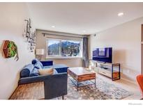 Bright living room with a blue sofa, wooden coffee table, and mountain views through a large window at 1201 Balsam Ave # 203, Boulder, CO 80304