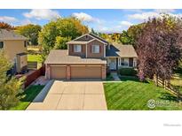 Charming home with a three car garage, lush green lawn, and mature landscaping at 148 Summerfield Ct, Erie, CO 80516