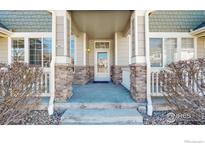 Inviting front porch with stone accents and covered entry, a warm welcome to this lovely home at 16047 E Geddes Ln # 128, Aurora, CO 80016
