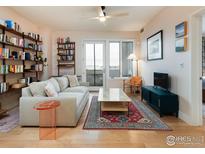 Inviting living room featuring a comfortable couch, stylish rug, bookshelf, and balcony access at 3701 Arapahoe Ave # 304, Boulder, CO 80303