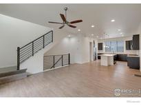 Bright and airy living room featuring a staircase with a black metal railing and an open-concept kitchen with wood floors at 415 Primrose Ln, Superior, CO 80027