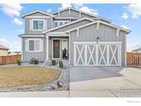 Charming gray two-story home with a well-manicured lawn and decorative garage door at 601 Tenderfoot Dr, Berthoud, CO 80513