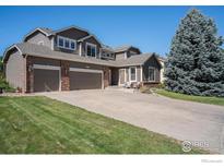 Charming two-story home featuring a well-manicured lawn, three-car garage, and beautiful mature trees at 11725 Montgomery Cir, Longmont, CO 80504